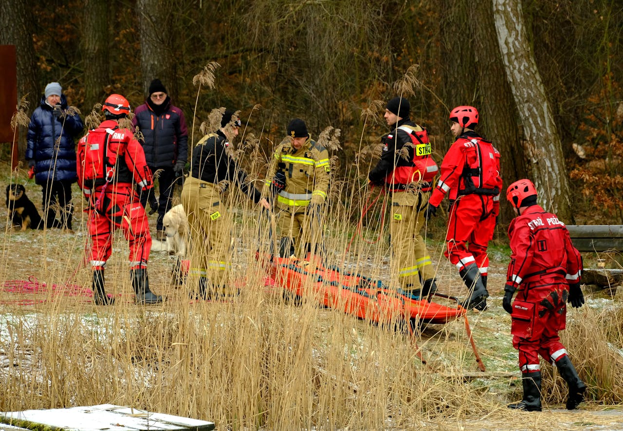 Rescue team conducts training exercise in forest clearing in winter.